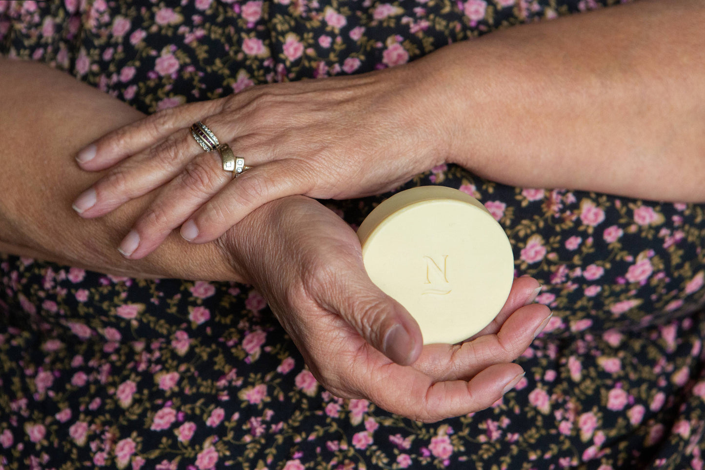 Person holding a Nopalera lotion bar with wearing a floral dress.
