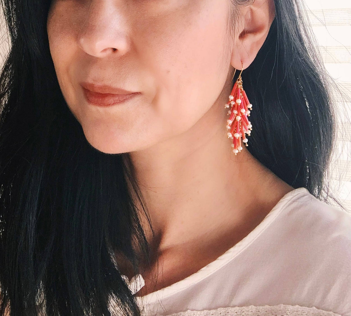 Close-up of a person wearing pink and pearl earrings with a blurred background