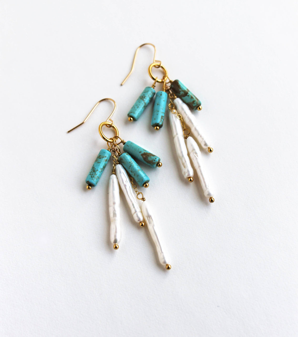 Pair of earrings with turquoise and pearl beads on a light background