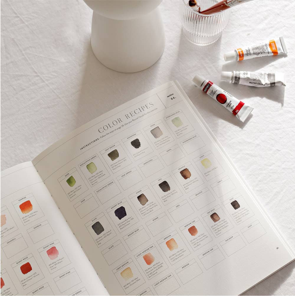 Color swatch book with paint tubes on a light surface