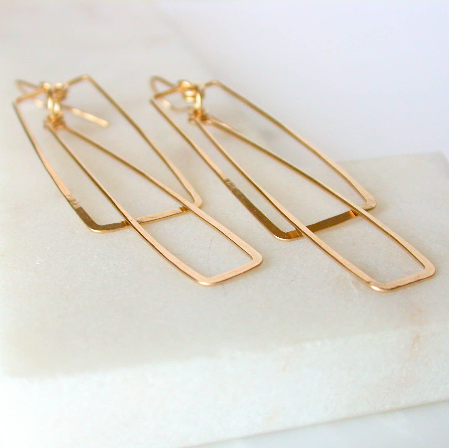 Rectangular Gold double hoop earrings on a white surface