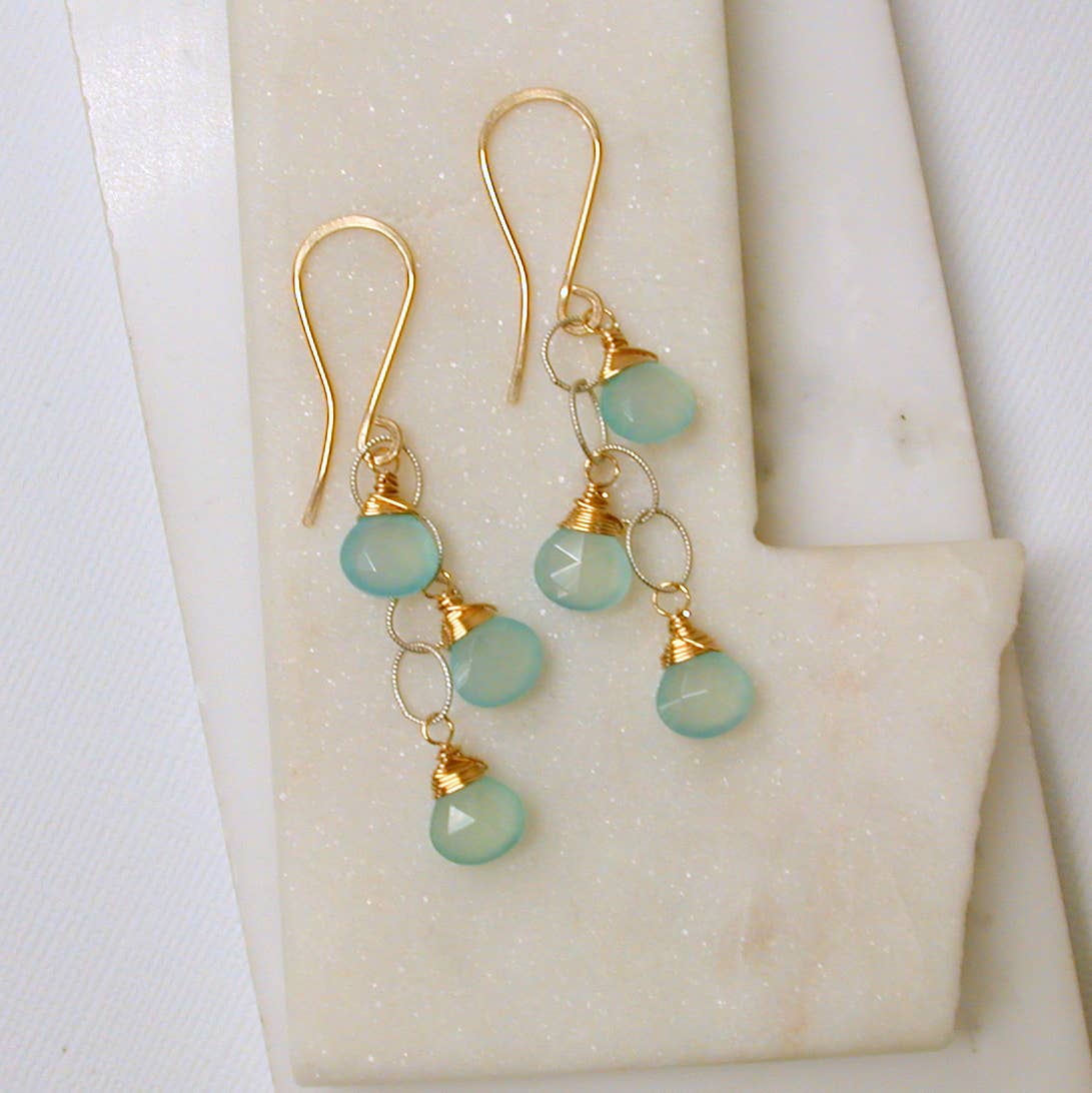 Gold dangle earrings with green chalcedony beads on a white background