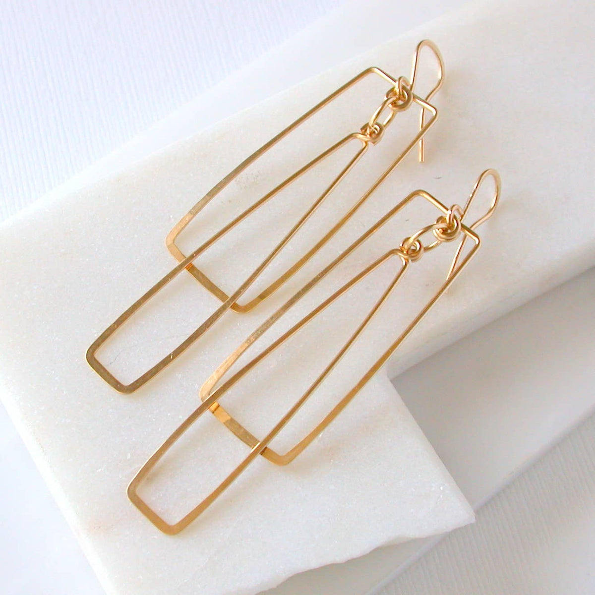 Rectangular Gold double hoop earrings on a white surface