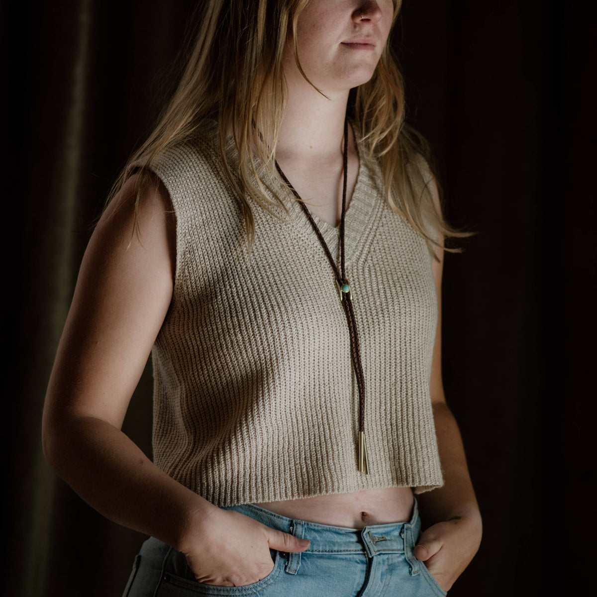 Brown and turquoise bolo tie on a woman with beige sleeveless top