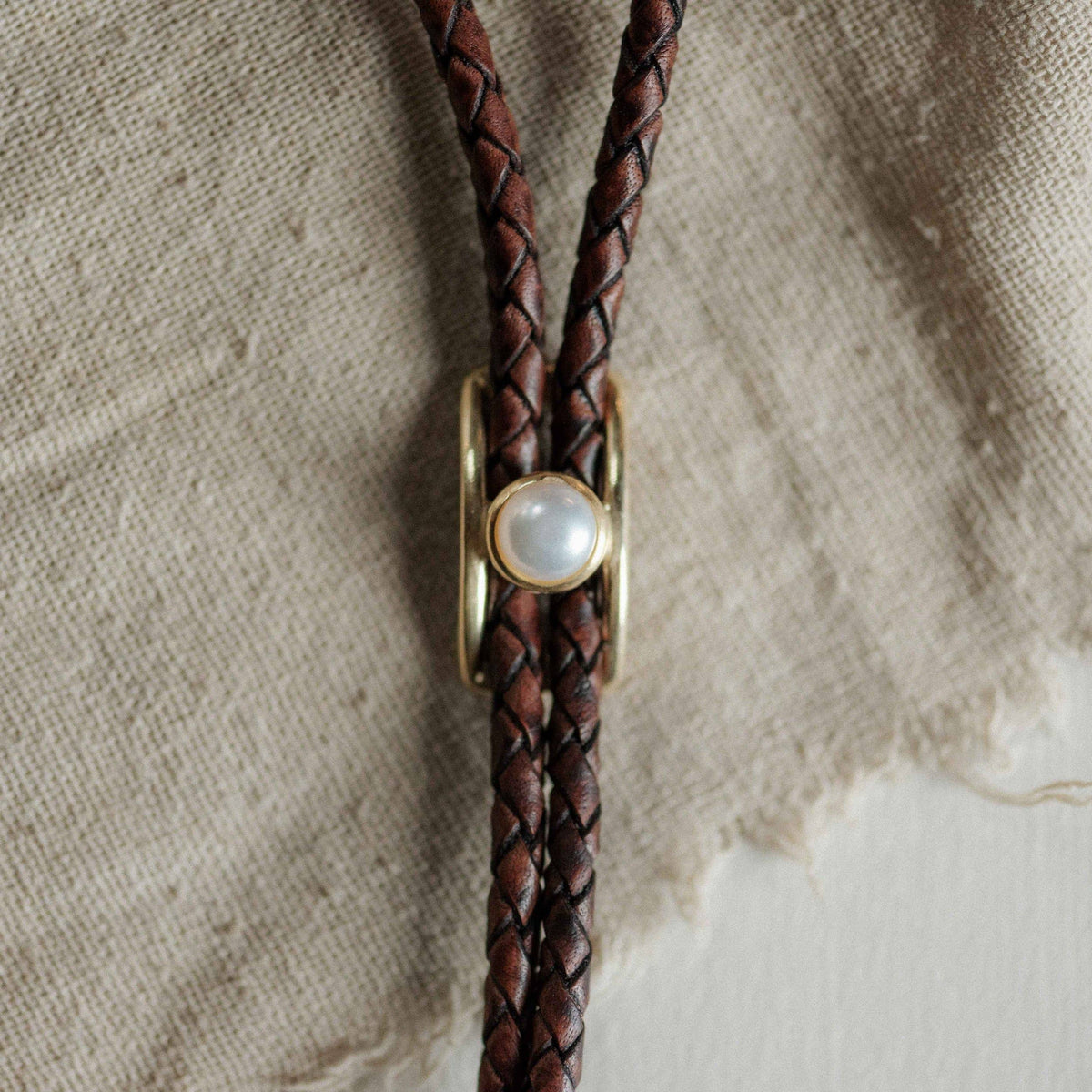 Brown leather bolo tie with pearl and brass slide
