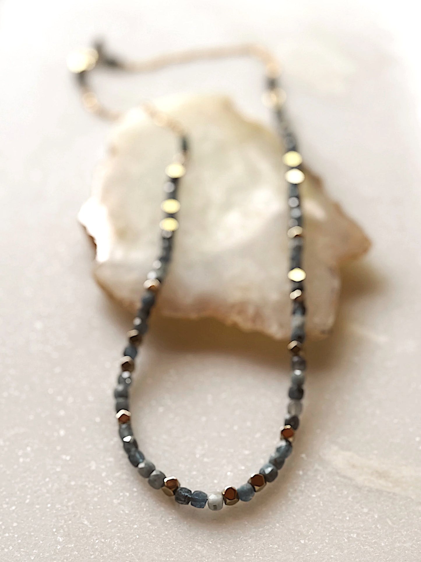 Necklace with small blue and gold beads on a white surface
