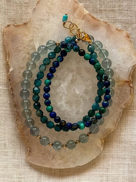 Green and blue beaded wrap bracelet on a stone surface