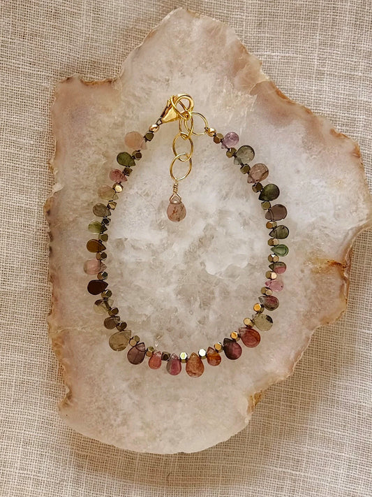 Multicolored beaded gemstone bracelet on a crystal plate with a stone background