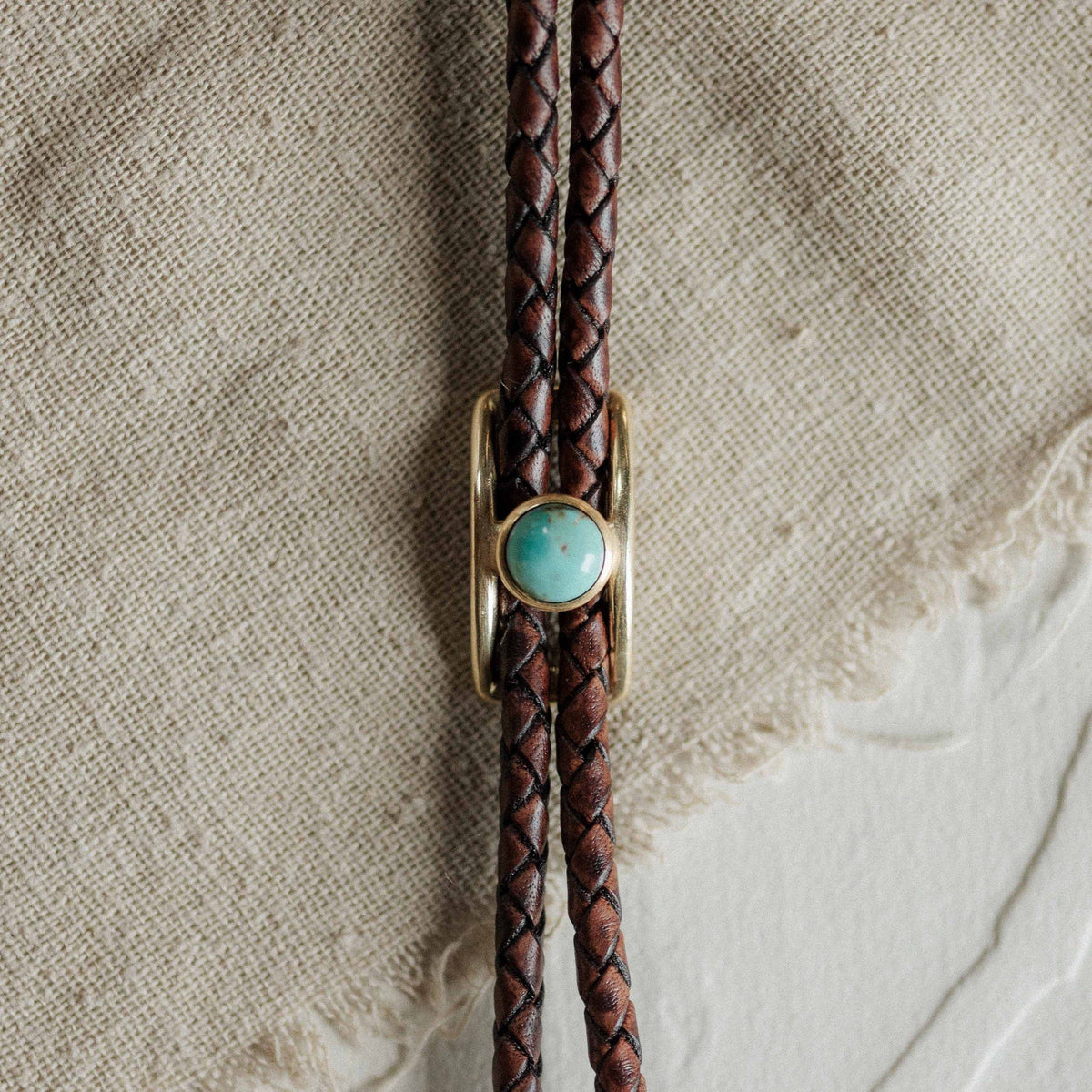 Brown leather bolo tie with turquoise and brass slide