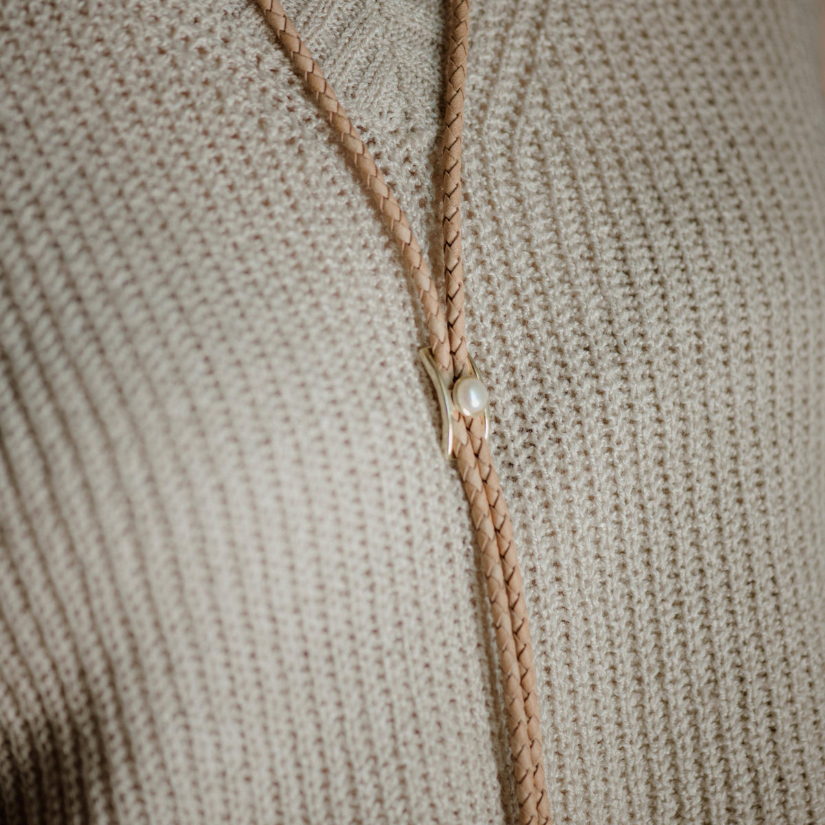 Natural leather and pearl bolo tie close up on sweater